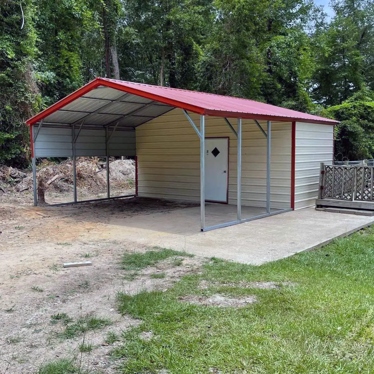 Tan metal utility carport with red roof and white door.