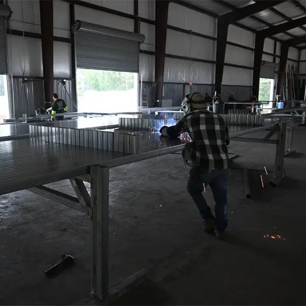 Skilled welder fabricating the base rail framework for a metal building.